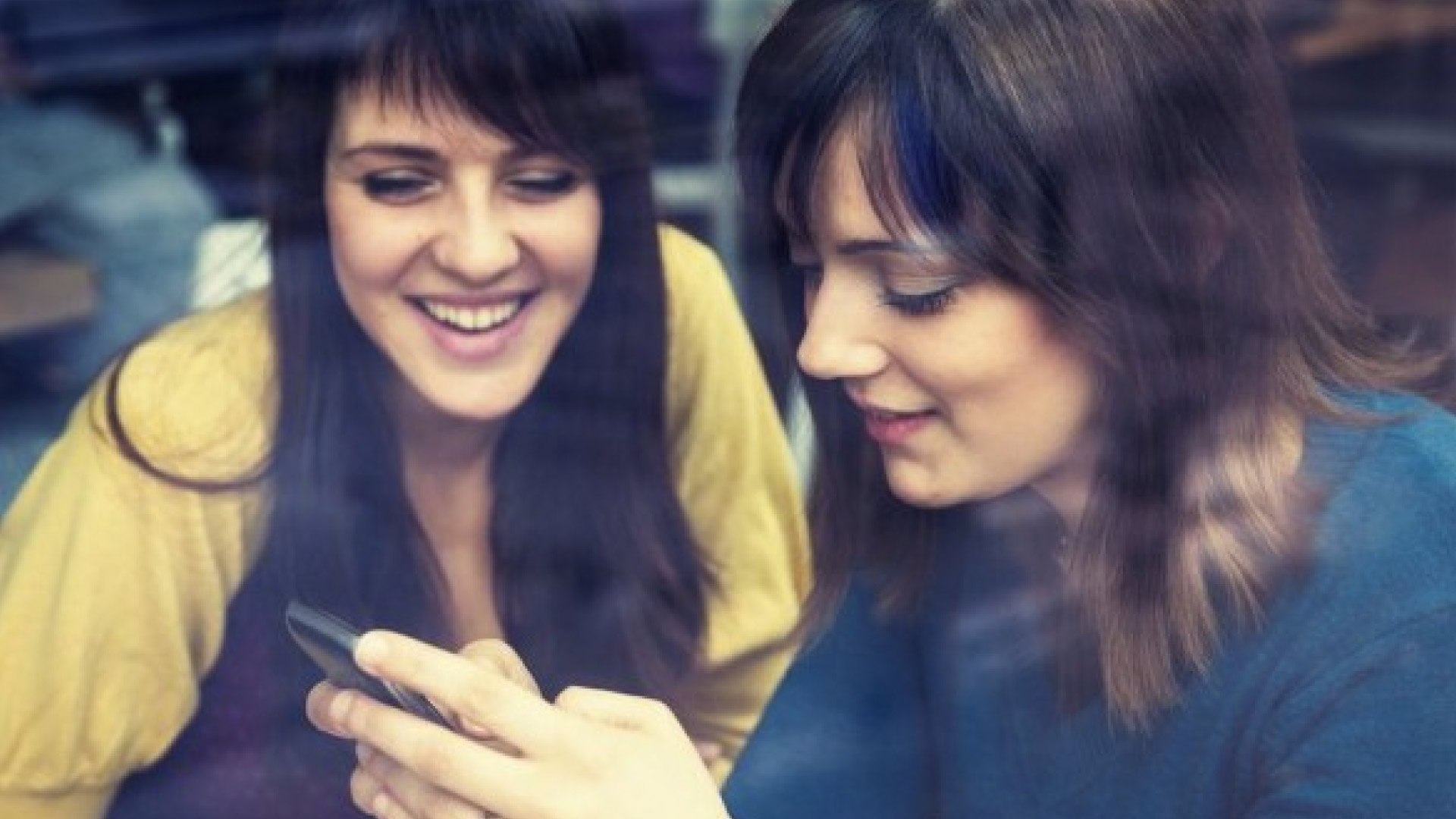 two girls laughing looking at a phone