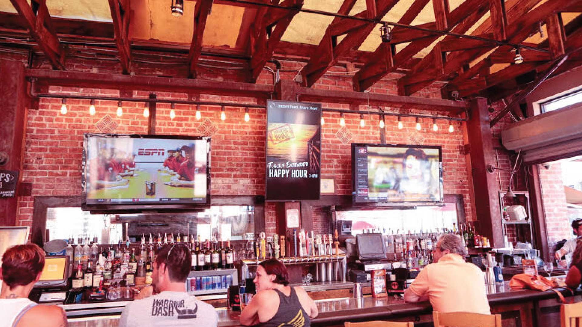 people sit at a bar with displays on the wall