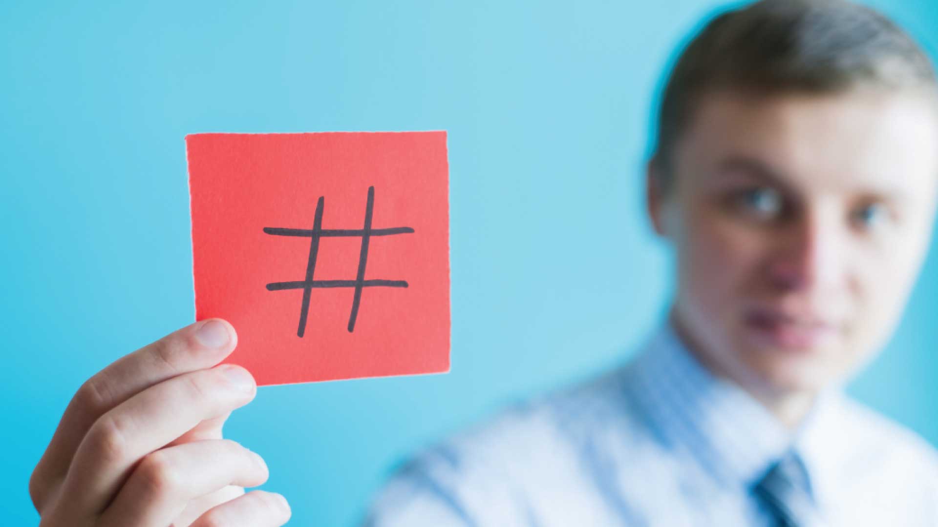 man holding a post it with a hashtag drawn on it