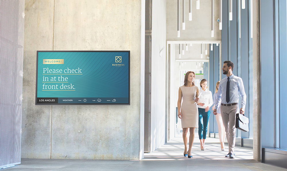 Man and woman walk past a descriptive sign in a hotel hallway