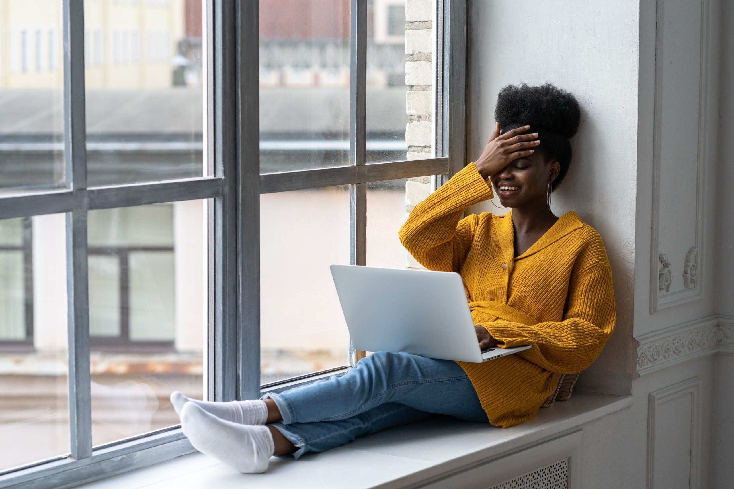 woman holds head while working on computer