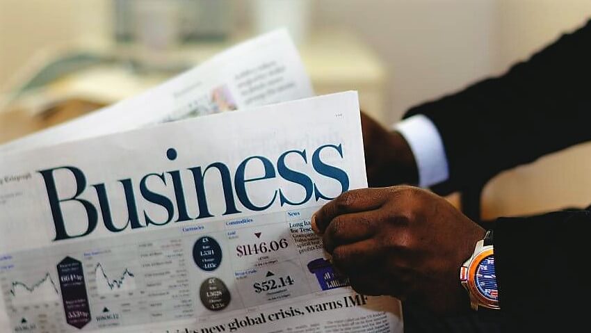man opening newspaper with headline of "Business"