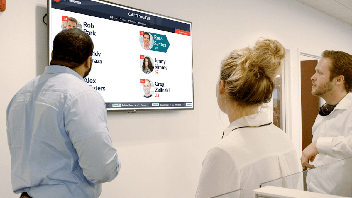 three workers looking at a display showing photos of people