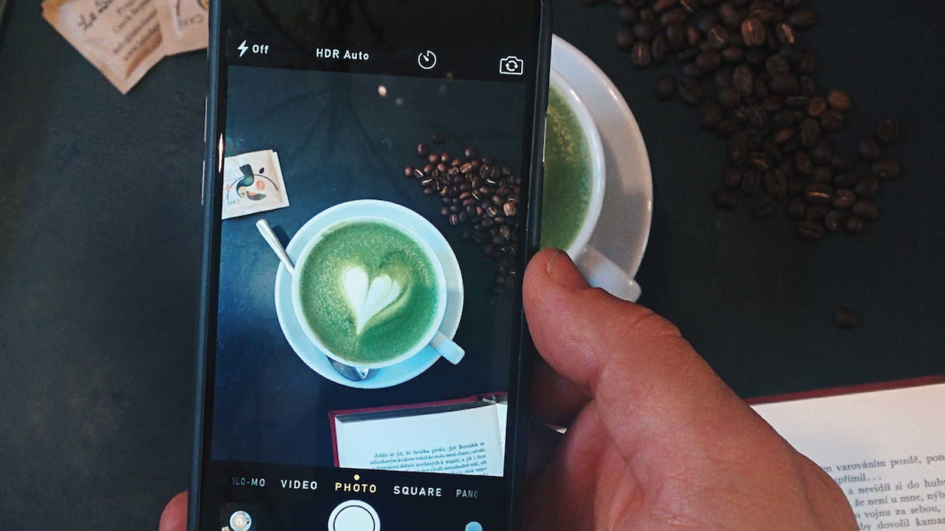 person taking a photo of their tea, decorated with a heart