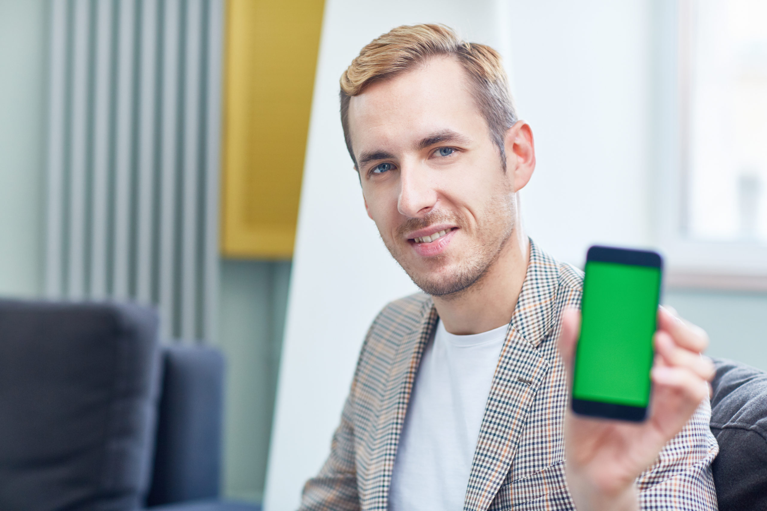 man in suit smiling showing his phone diplay