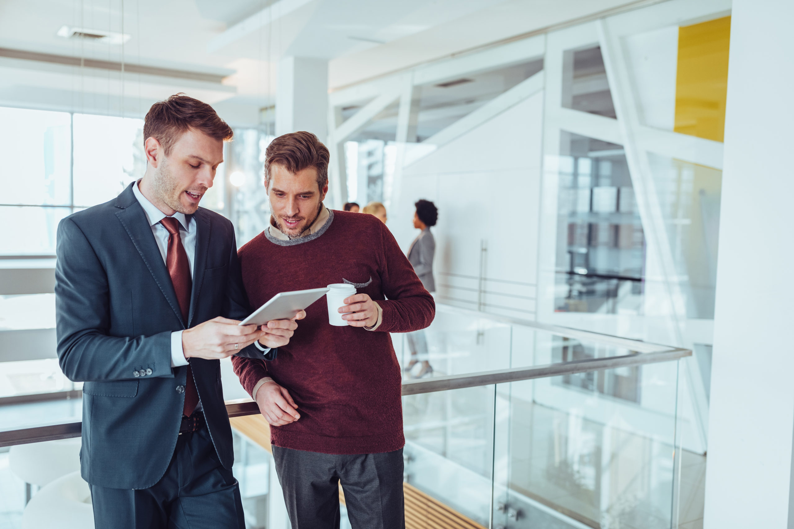 man in suit showing another man something on a tablet