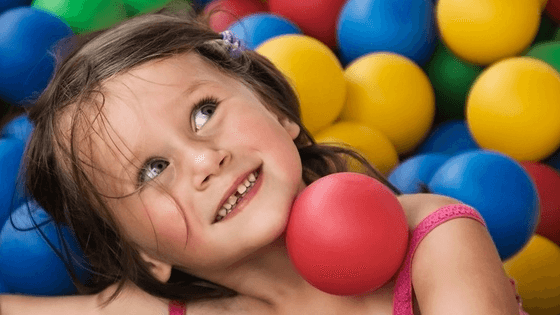 young child plays in plastic balls