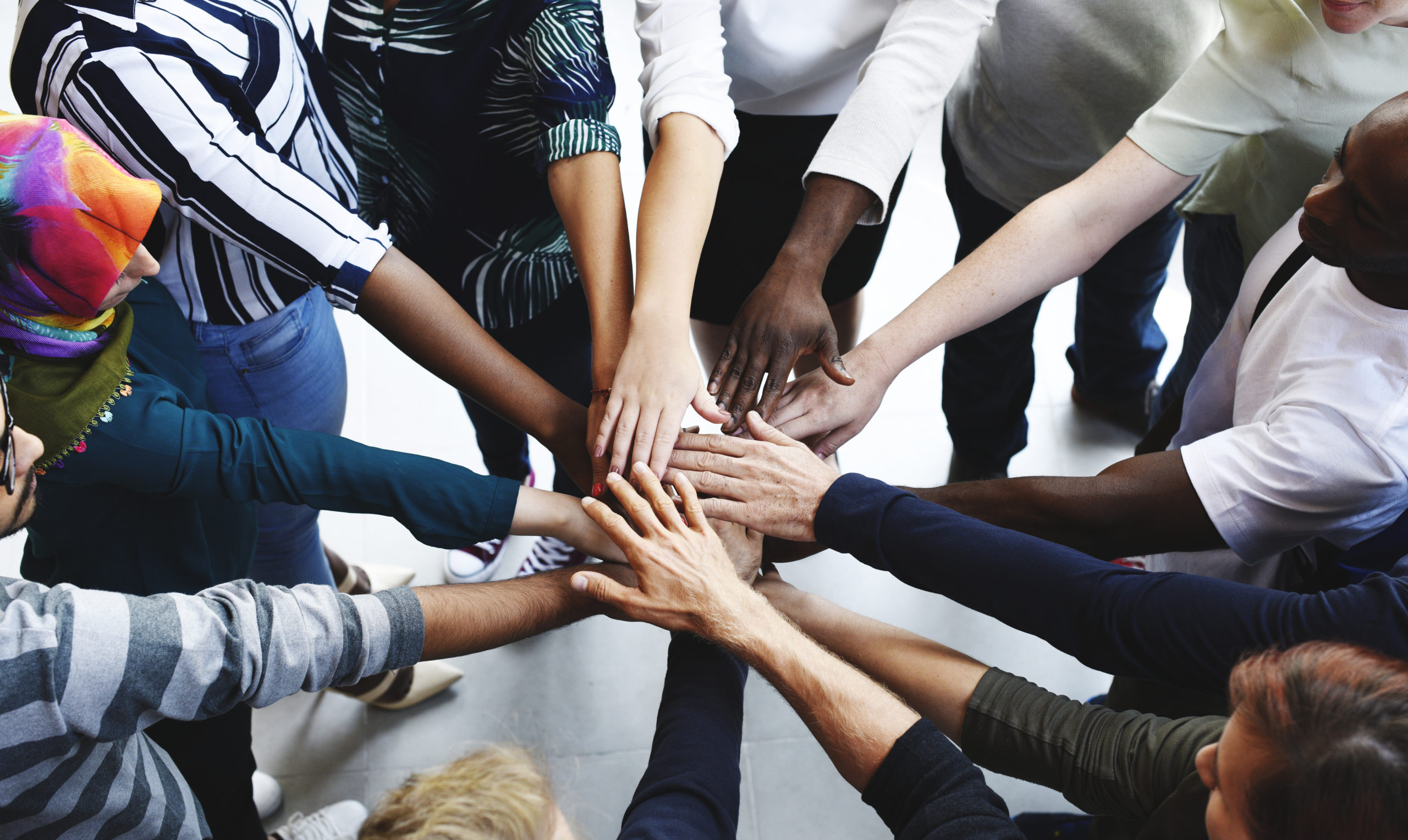 a diverse team joing hands in the middle of a circle