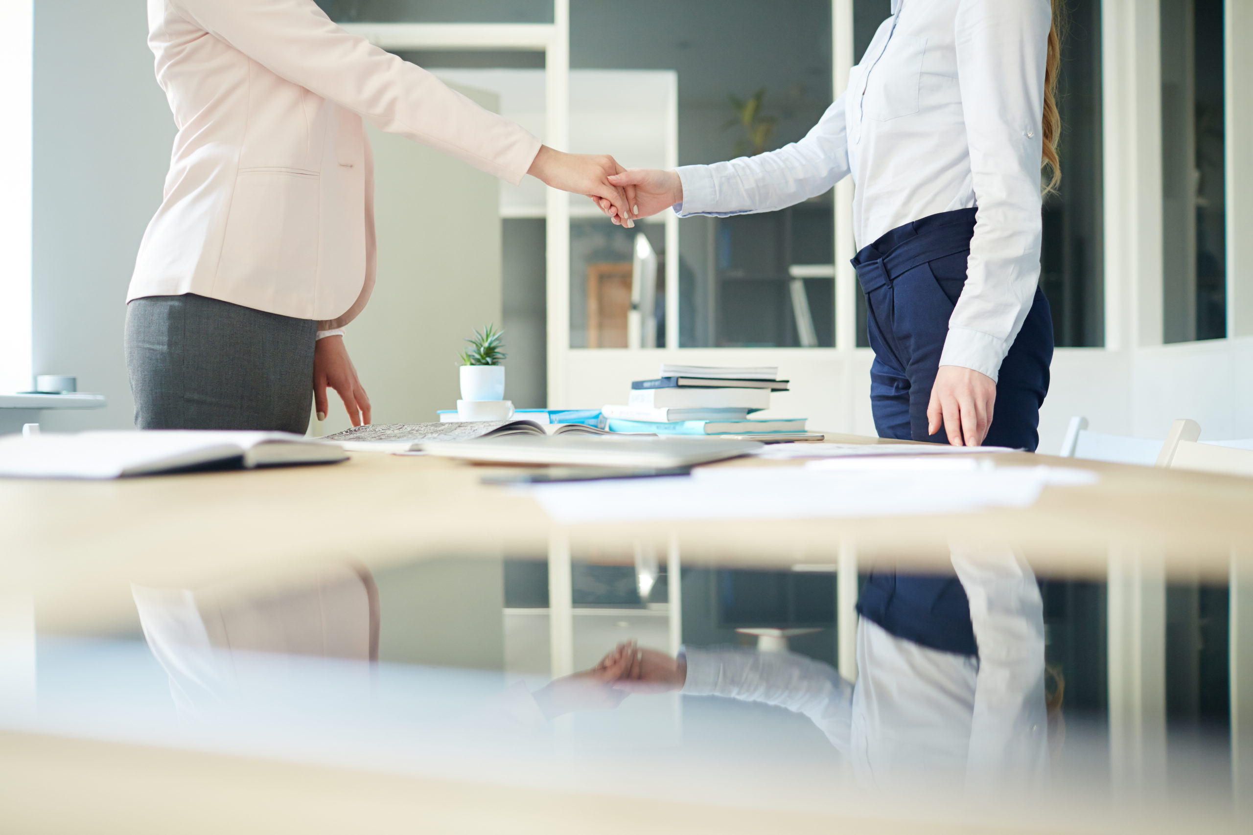 employees shake hands over a desk