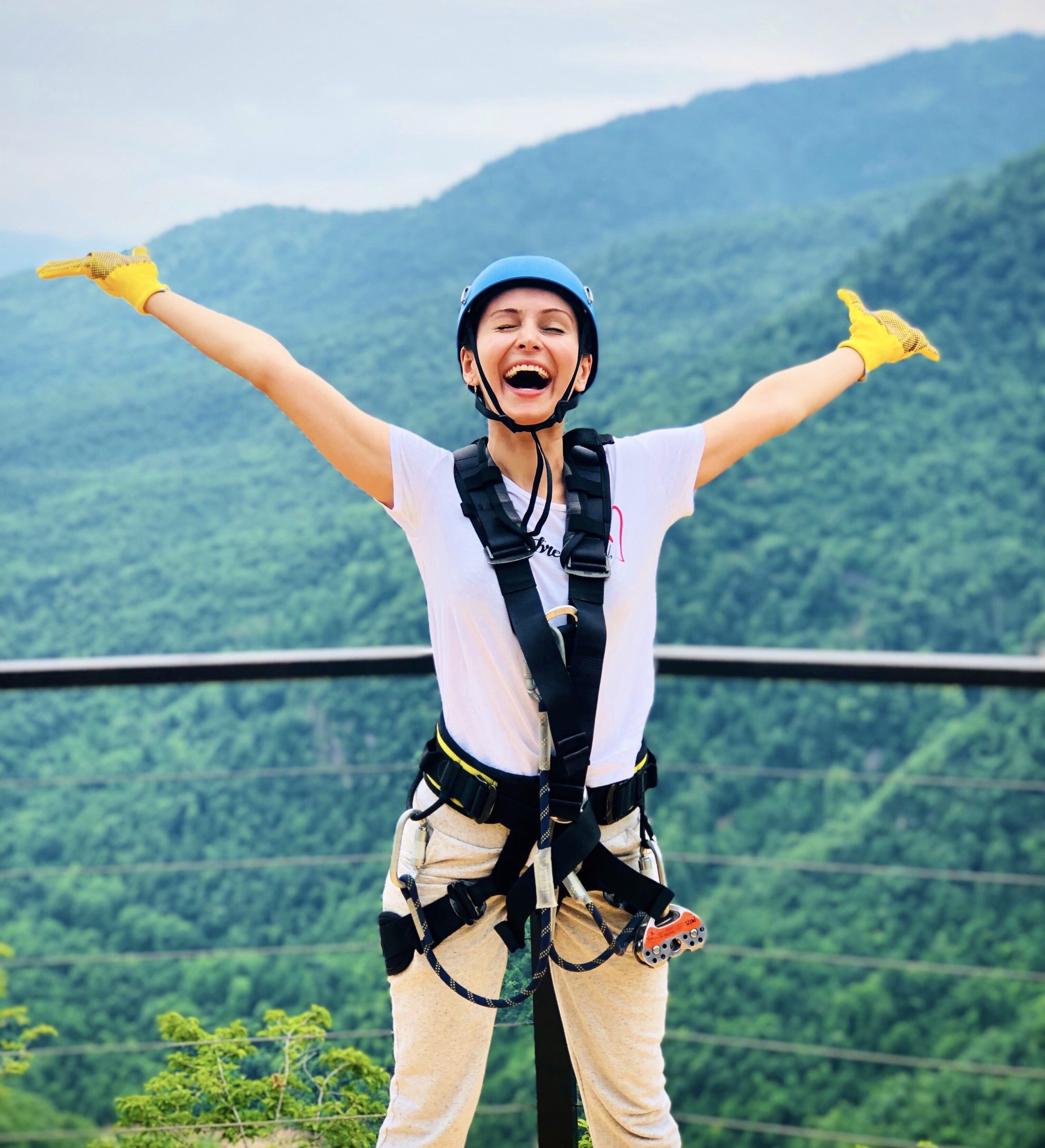 person celebrating atop a peak with safety gear on
