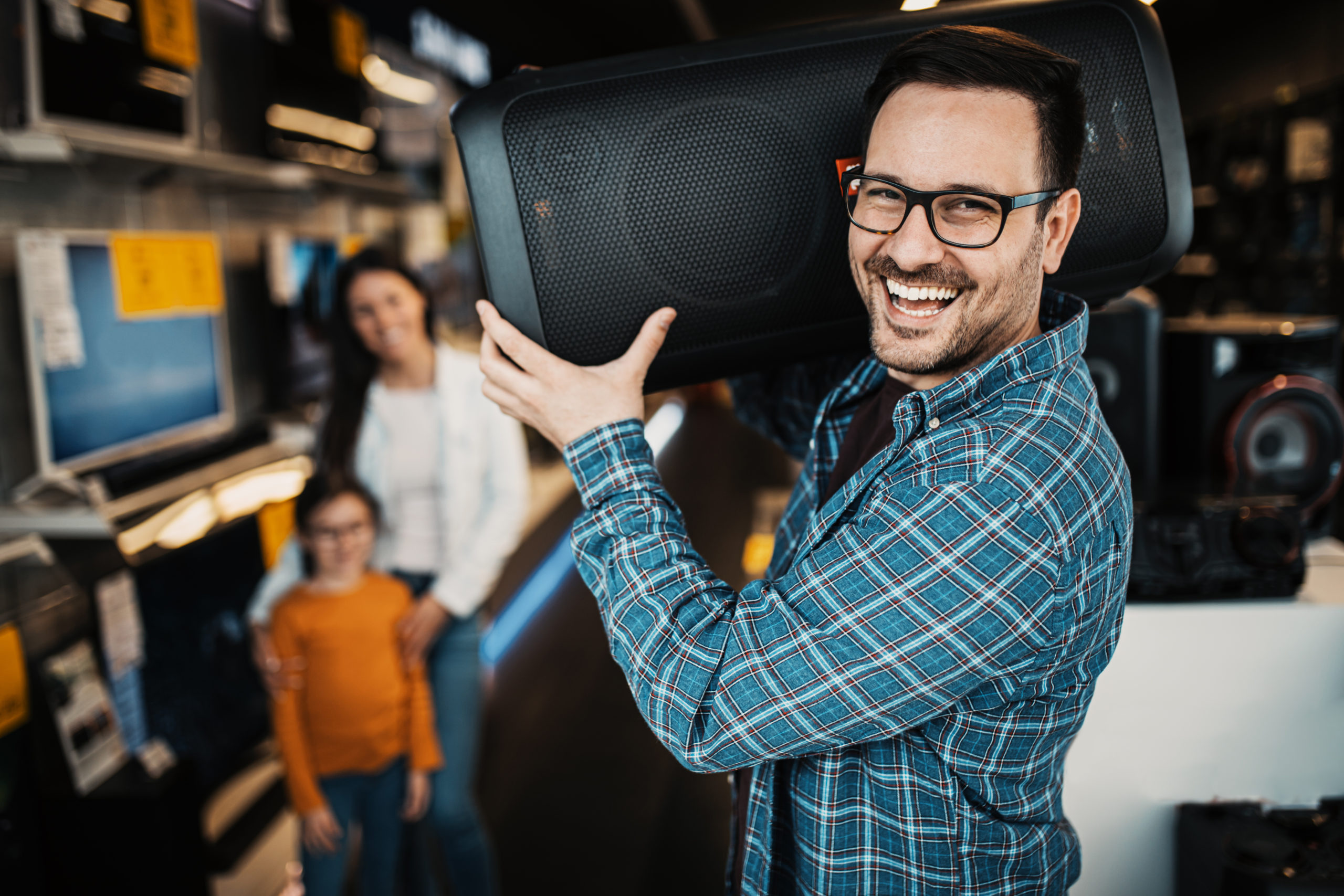 Happy family buying large music speaker in tech store.