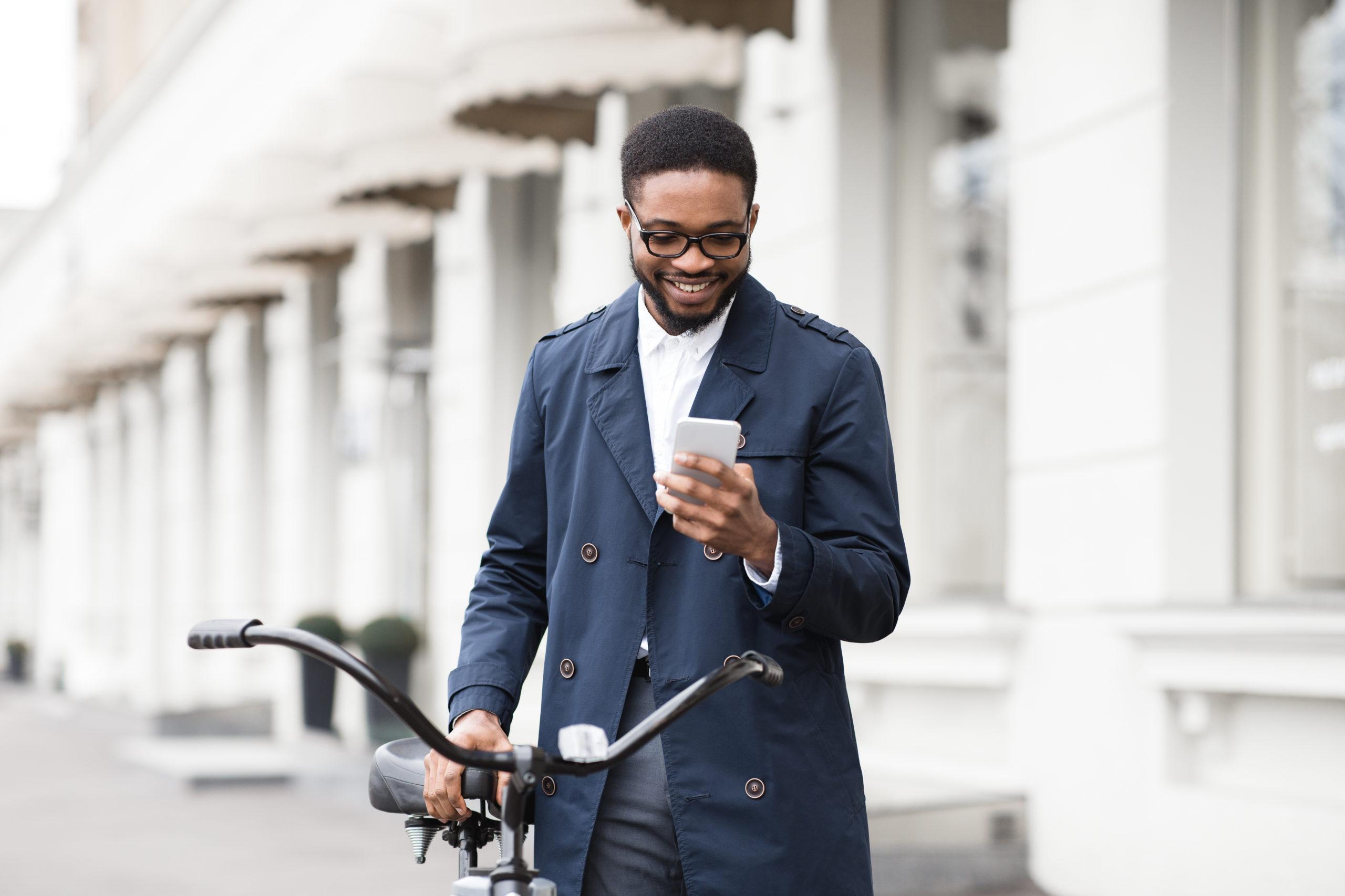 man holding bicycle in front of building on his phone