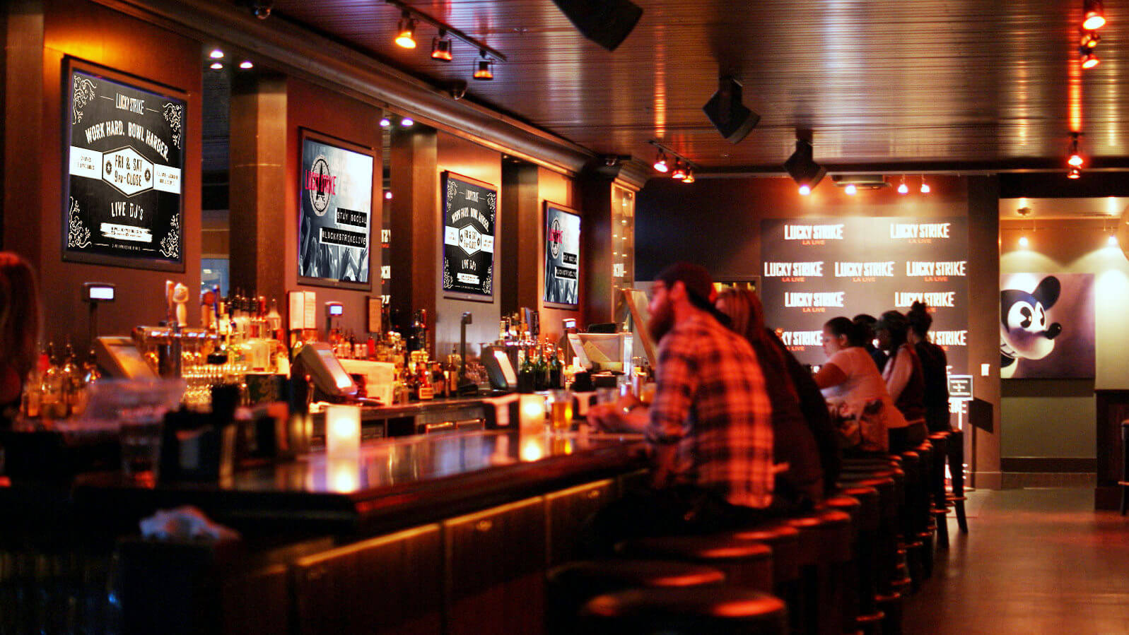 few people sit at a dimly lit bar looking at displays