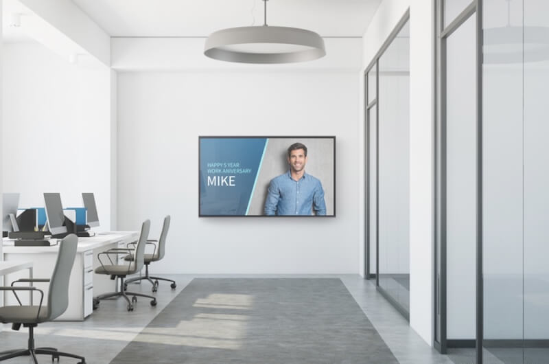 Open office with a digital sign recognizing an employee work anniversary