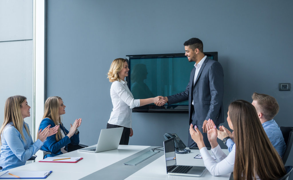 workers congratulation an employee in a conference room