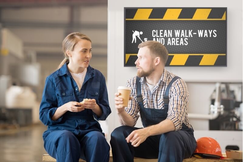 manufacturing workers on break in front of safety signage