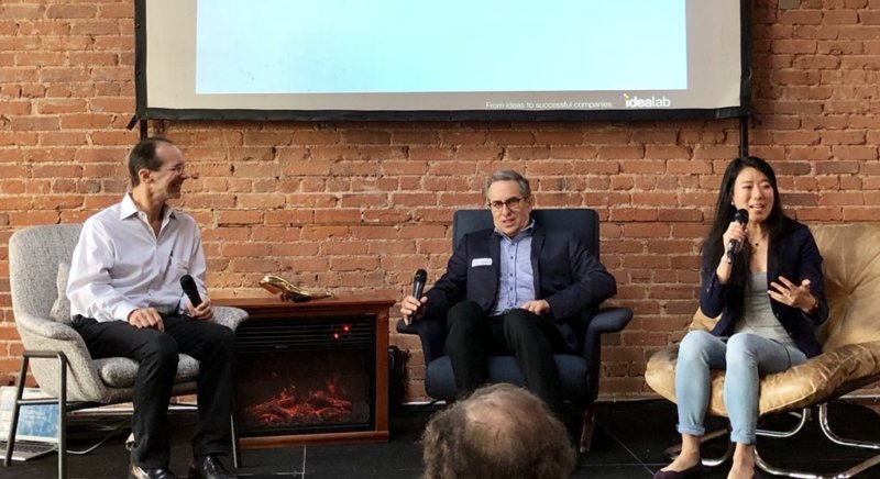 three people under a display doing an interview in front of people