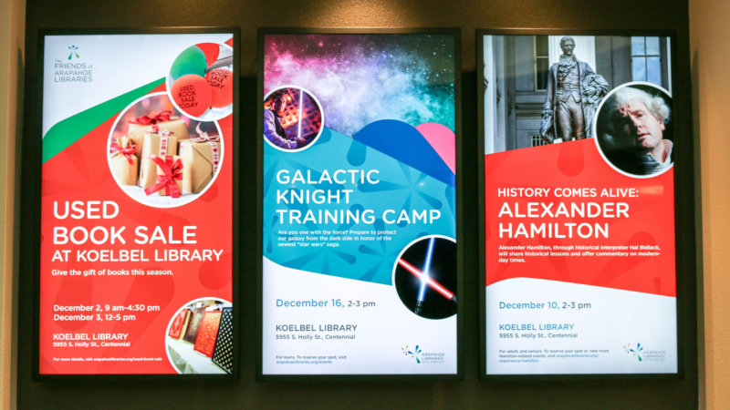 Wall of three digital poster displays at Arapahoe Libraries powered by Enplug