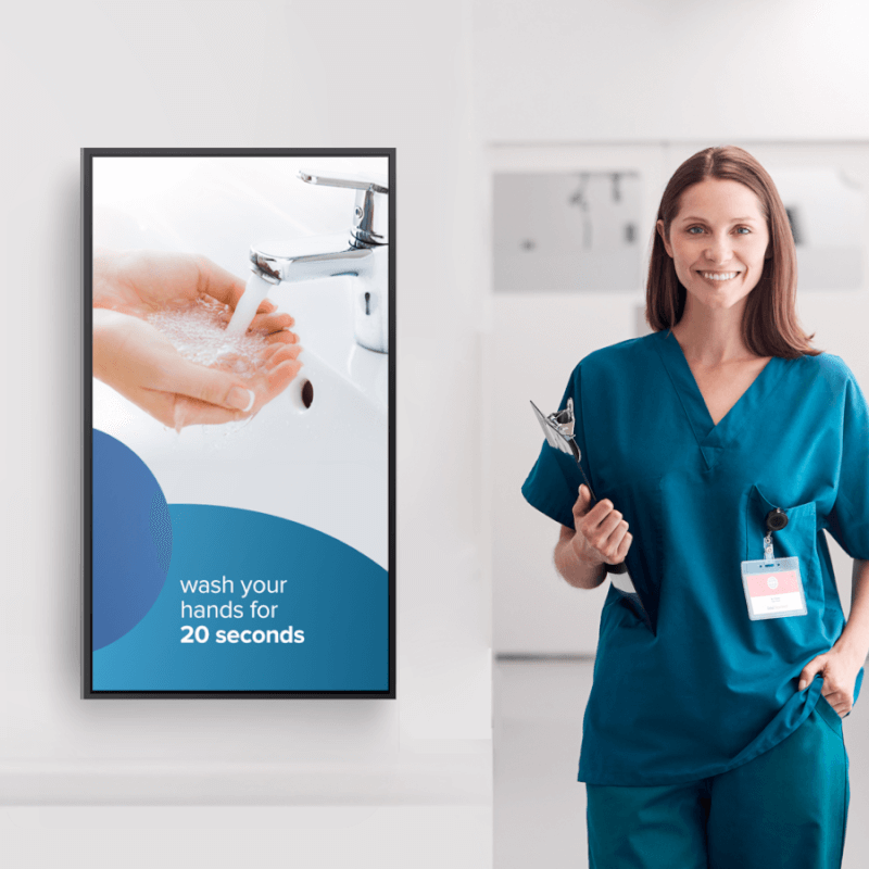 nurse standing next to a display with hand washing instructions