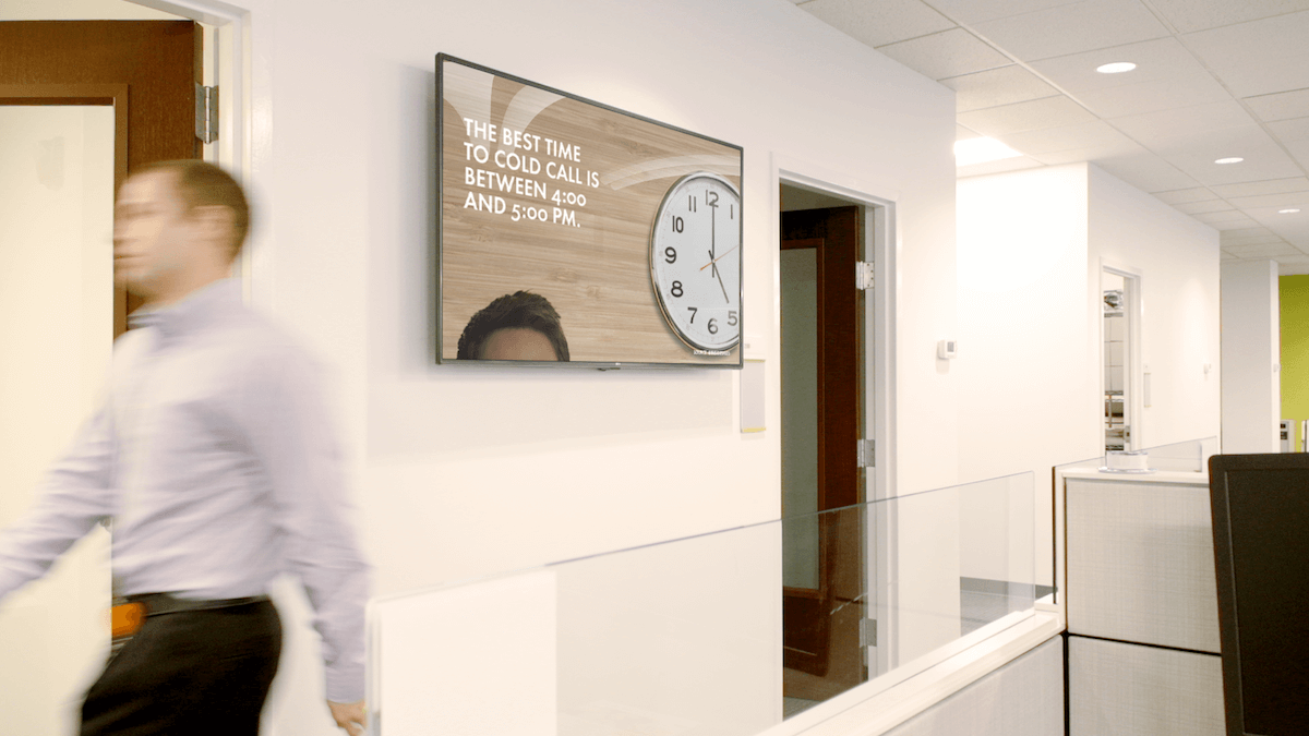 man walking through office by a tv display