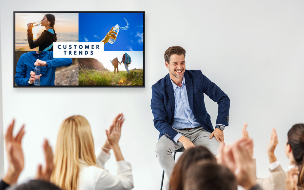 man receiving applause after giving presentaion with a digital display behind him