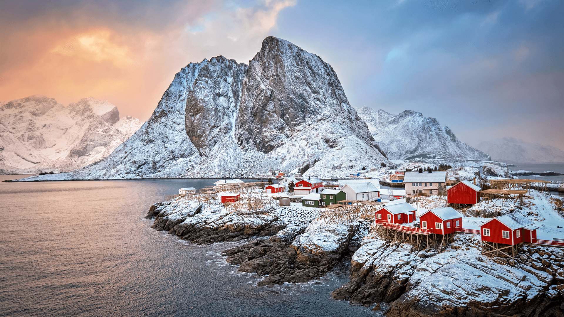 beautiful snow covered mountain landscape on a lake with red houses along cliffs