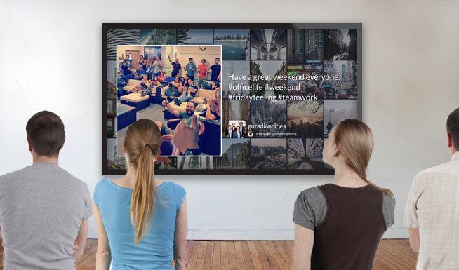 four people looking at a large wall display screen