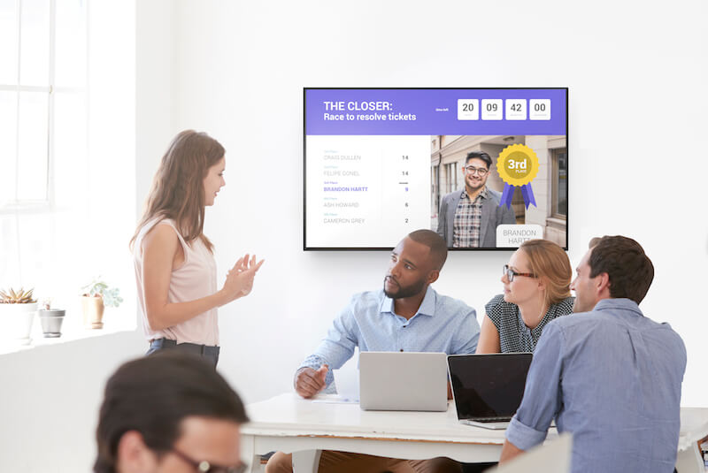 employees discussing ideas around a desk with a display