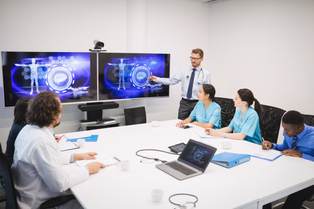 man giving presentation in small room with two large digital displays