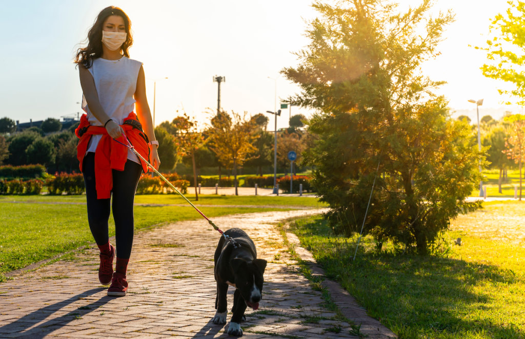 woman walking dog outside with mask on