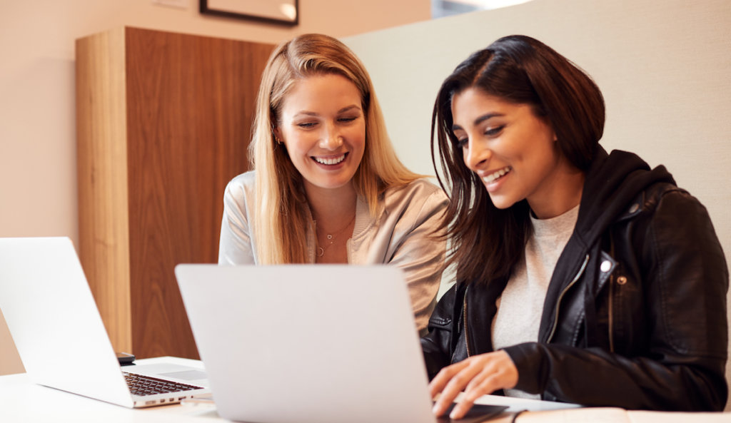 two frinds working at a computer together