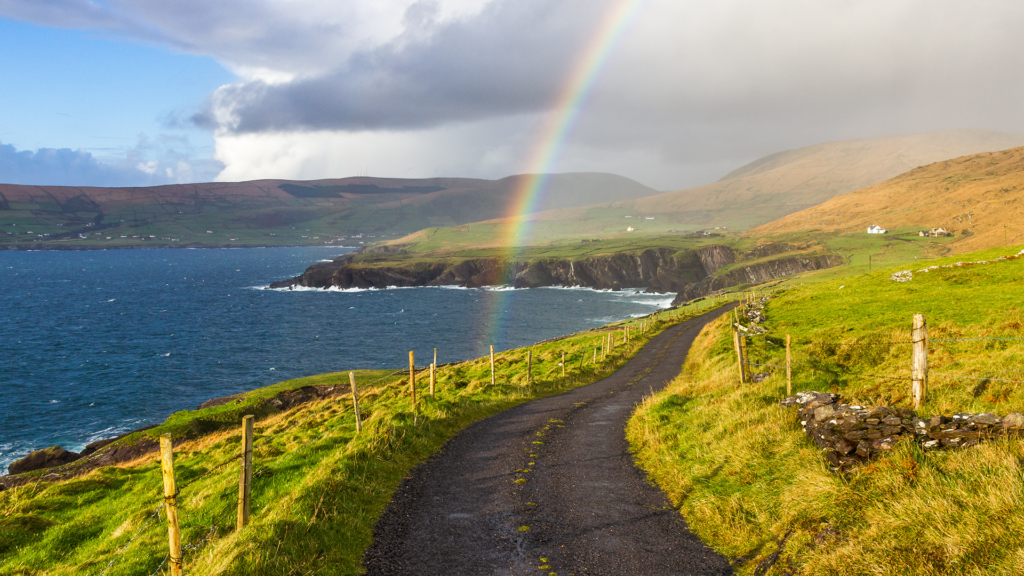 rainbow coming down over a road along the water