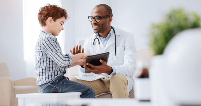 doctor using a digital tablet while talking to young child patient