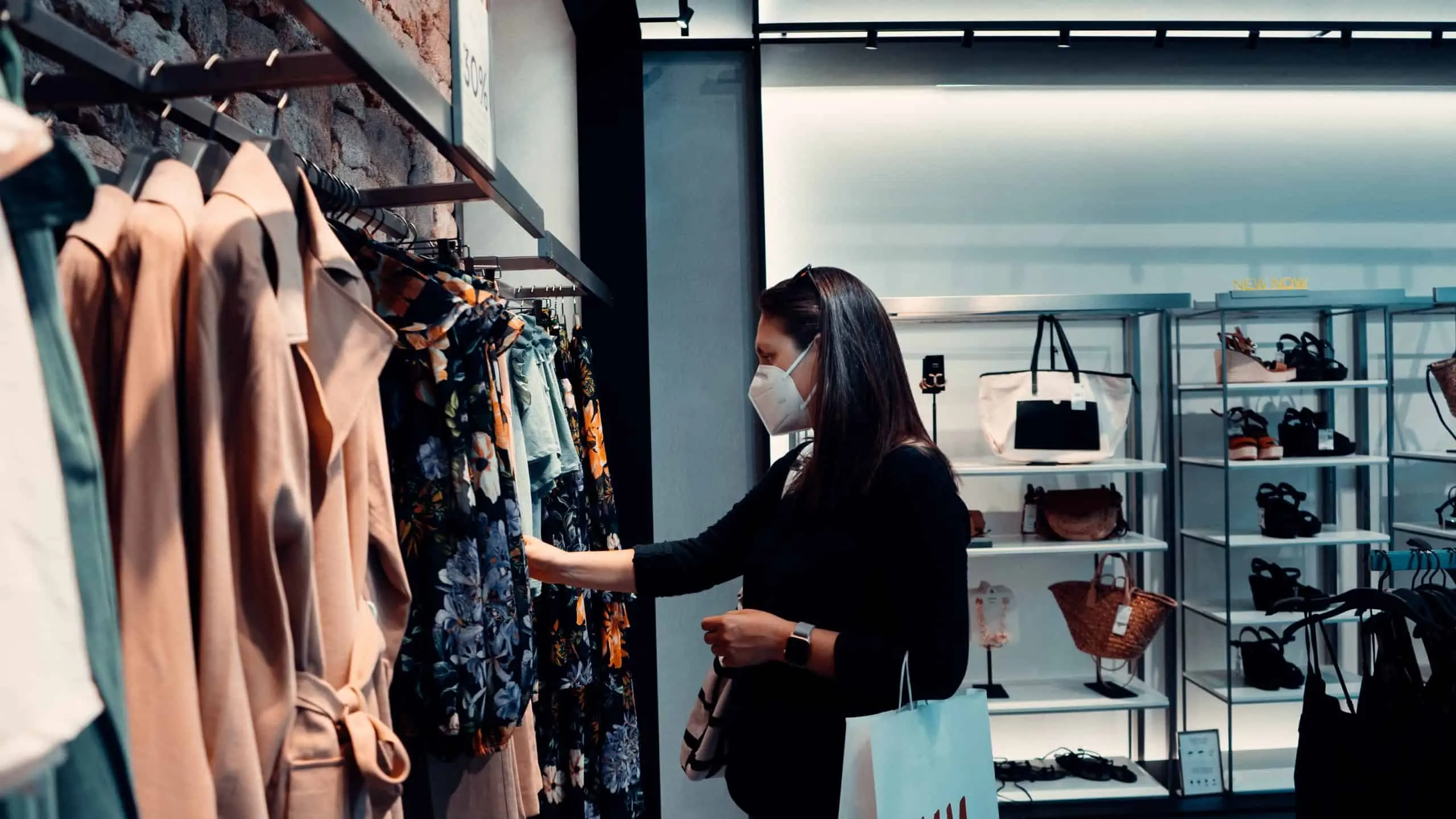 lady shopping looking at clothes with a mask on