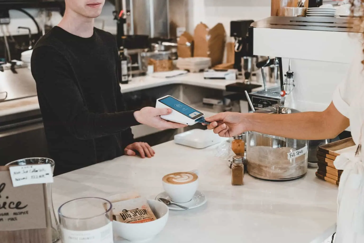 Customer paying for coffee at a counter using a credit card reader
