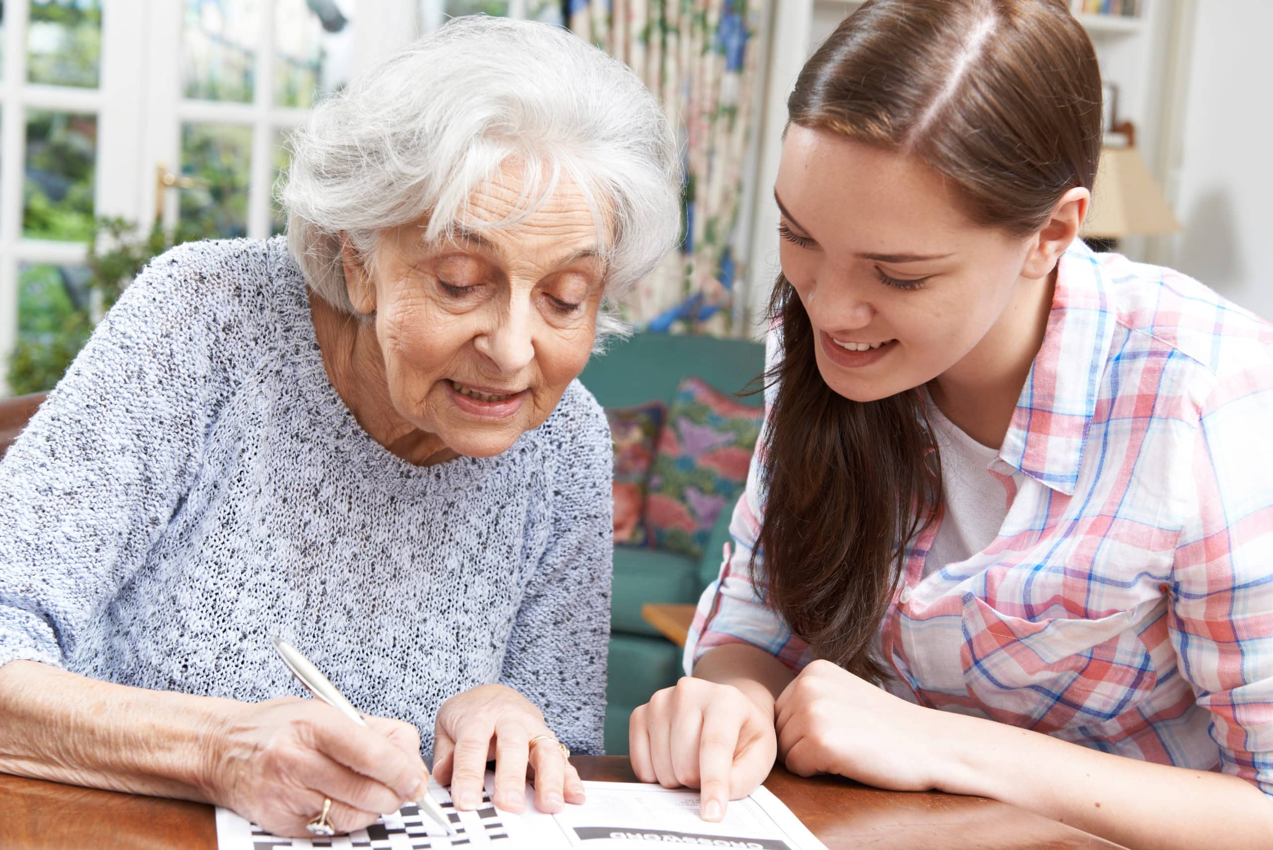 Elderly woman doing crossword with younger woman