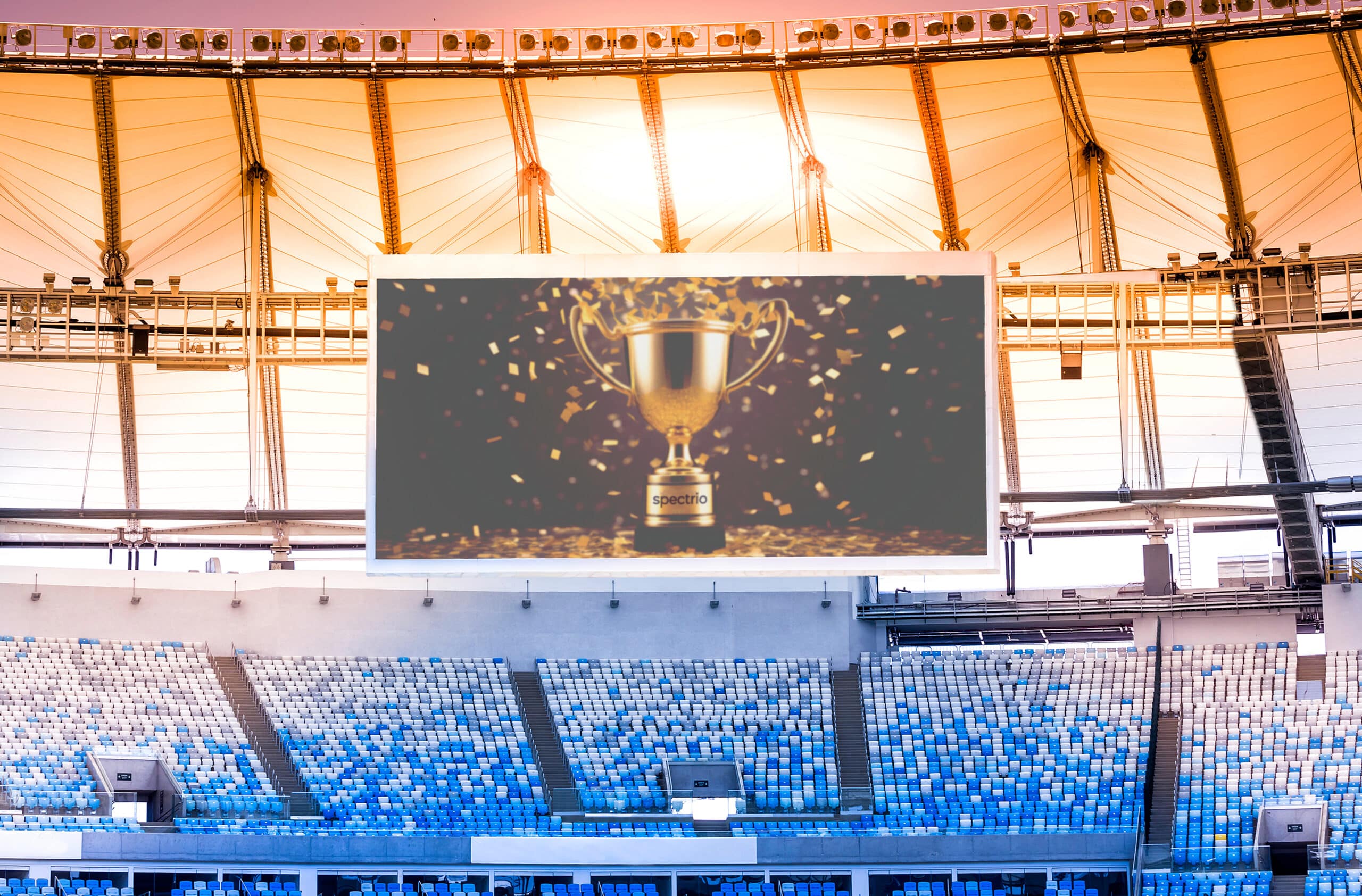 Large video screen hanging in a stadium with an image of a trophy with confetti and the inscription of Spectrio on the base
